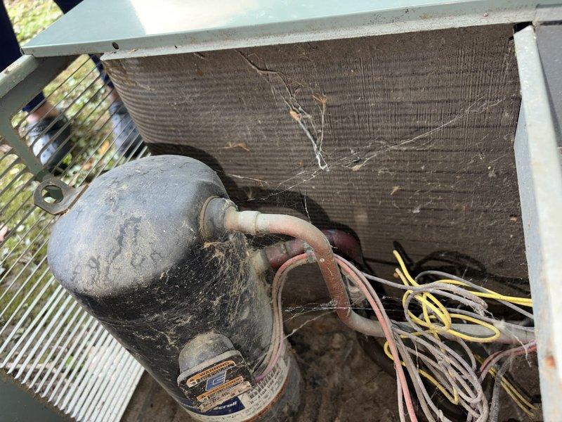 Completed routine maintenance visit on aging air conditioning system as part of ongoing preventive maintenance program. Upon inspection, found significant dust, dirt, and cobweb accumulation throughout unit interior, including on compressor housing, evaporator coil fins, and electrical components. Documented equipment condition through photographic evidence showing debris buildup on heat exchanger coils and various mechanical components, which can reduce system efficiency and airflow if left unaddressed.