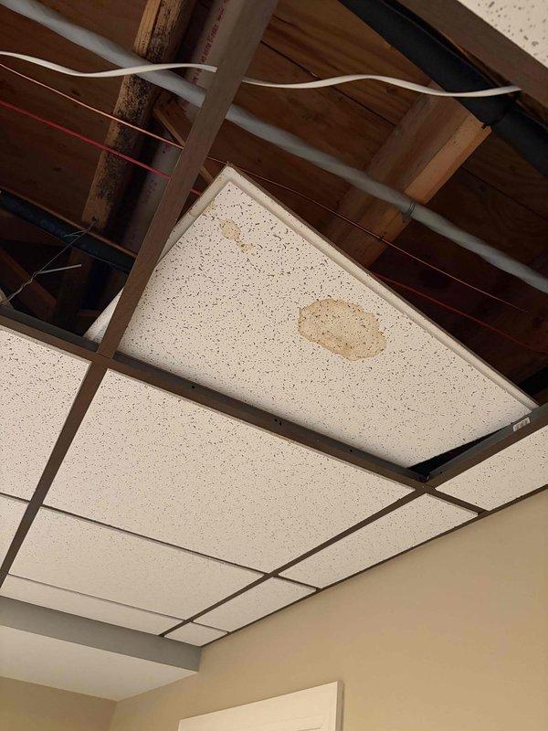 Completed quality check inspection of HVAC system and surrounding ceiling infrastructure. Documented ceiling conditions including exposed plenum area with visible wiring runs, acoustic tile configuration, water staining on ceiling tiles, and LED lighting fixtures. Photographed current system status for record-keeping purposes.