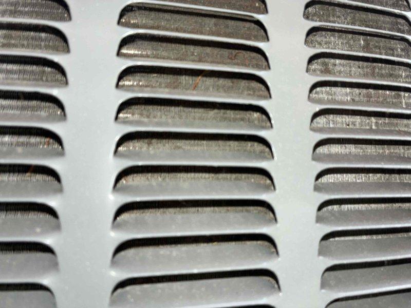 Completed preventive maintenance inspection on residential cooling system. Accessed outdoor condensing unit, inspected electrical components including capacitor and CoreSense diagnostic module with associated wiring connections. Observed normal dirt and debris accumulation on base panel and interior surfaces consistent with regular operation. Inspected condenser coil fins for proper condition and airflow. Checked supply vent grill showing typical wear and minor surface oxidation. All components found operational within normal parameters for ongoing seasonal maintenance program.