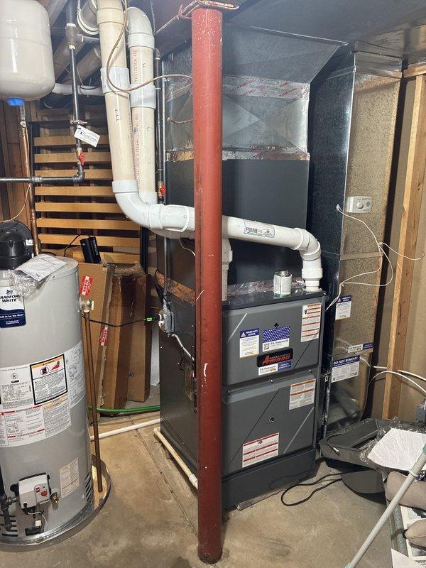 Completed full HVAC air conditioning system installation including outdoor condenser unit mounted on concrete pad with proper gravel bed landscaping and indoor air handler with associated ductwork and PVC condensate drainage in basement utility area. Installed electrical disconnect box on exterior wall with proper conduit and wiring connections, verified all refrigerant lines properly insulated and secured, and confirmed system operational with appropriate airflow and cooling capacity.