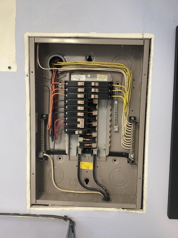Conducted comprehensive on-site electrical assessment for generator installation and knob-and-tube wiring replacement. Documented existing electrical panel configuration, including current breaker arrangement, circuit labeling, and wire routing. Photographed 100-amp or 150-amp main service panel showing dual-column breaker layout with circuits serving range, appliances, garbage disposal, dishwasher, air conditioning units, hood, and microwave. Evaluated panel capacity and available spaces for generator interlock or transfer switch integration. Assessed copper conductors, grounding bar connections, and neutral wire terminations. Identified knob-and-tube wiring requiring replacement to meet current electrical code standards. Prepared estimate documentation for both generator backup power system installation and complete rewiring project to eliminate obsolete wiring methods.