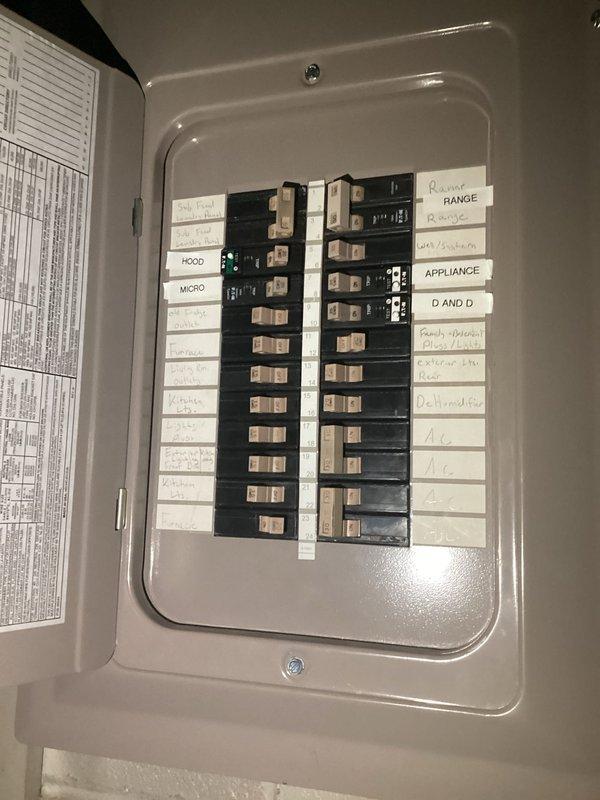 Conducted comprehensive on-site electrical assessment for generator installation and knob-and-tube wiring replacement. Documented existing electrical panel configuration, including current breaker arrangement, circuit labeling, and wire routing. Photographed 100-amp or 150-amp main service panel showing dual-column breaker layout with circuits serving range, appliances, garbage disposal, dishwasher, air conditioning units, hood, and microwave. Evaluated panel capacity and available spaces for generator interlock or transfer switch integration. Assessed copper conductors, grounding bar connections, and neutral wire terminations. Identified knob-and-tube wiring requiring replacement to meet current electrical code standards. Prepared estimate documentation for both generator backup power system installation and complete rewiring project to eliminate obsolete wiring methods.