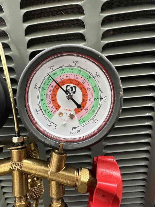 Completed routine HVAC cooling maintenance on air conditioning system. Performed system diagnostics including refrigerant pressure testing using manifold gauges, confirming pressures within normal operating range in the green zone for R-410A refrigerant. Measured electrical parameters with digital clamp meter, recording amperage draw of 22.2A and voltage reading of 11.01V to verify proper system operation and component performance.