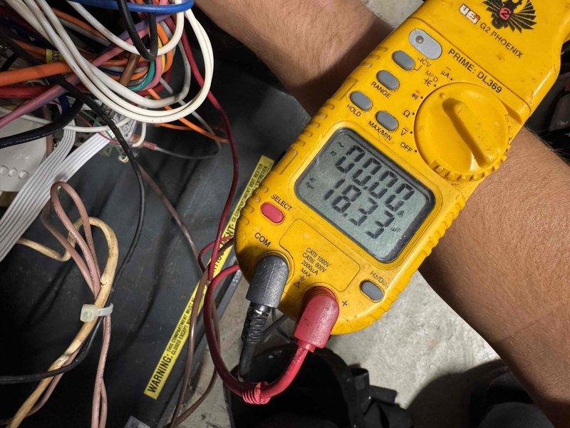 Responded to no cooling complaint on residential air conditioning system. Upon arrival, accessed basement mechanical room and performed diagnostic testing of HVAC equipment. Utilized digital multimeter to check electrical components and verify proper voltage and amperage readings at the air handler unit. Inspected furnace/air handler assembly, refrigerant lines, and associated electrical connections. Documented equipment conditions with photos showing overall system configuration including furnace unit with control panel, air handler with refrigerant line connections, and general mechanical room layout. Performed electrical diagnostics at component level to identify cause of cooling failure.