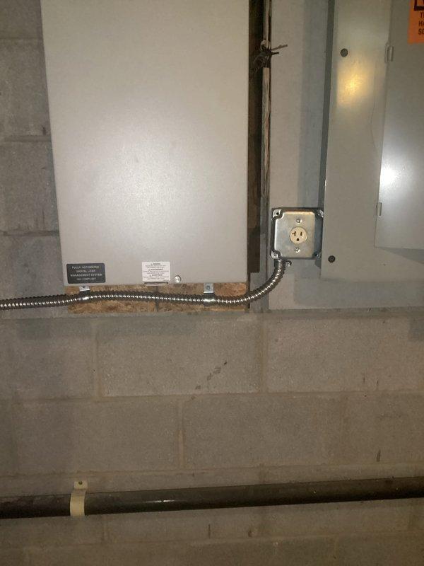 Installed dedicated electrical outlet for tankless hot water heater in utility area. Ran flexible metal conduit along concrete block wall from junction box to new heavy-duty outlet box, ensuring proper support and code-compliant installation. Documented completed installation with photographs showing conduit routing, outlet box mounting, and connection points in proximity to existing plumbing infrastructure.