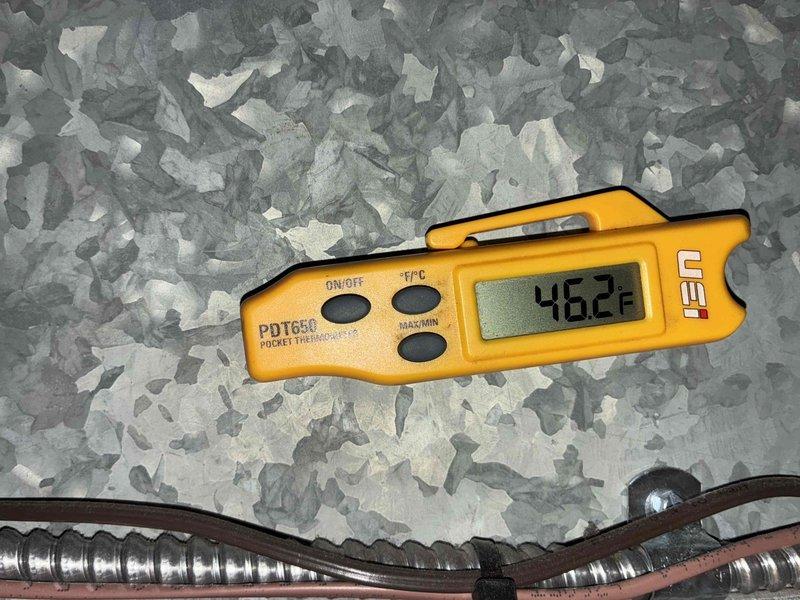Completed comprehensive cooling system maintenance on HVAC unit. Verified proper system operation by measuring supply air temperature at 46.2°F, confirming adequate cooling performance and refrigerant charge. Inspected condensate drain system with funnel assembly and PVC drainage piping to ensure proper moisture removal and prevent potential water damage or overflow issues.