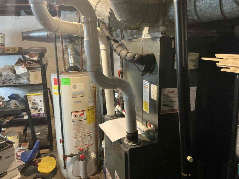 Conducted comprehensive on-site evaluation of existing residential HVAC system and water heating equipment to provide full system replacement options. Assessed current dark gray furnace/air handler unit and GE-branded cylindrical water heater located in basement mechanical room, documenting equipment specifications, condition, and installation configuration including all associated ductwork, venting, and piping connections. Presented customer with multiple equipment replacement options for both heating/cooling system and hot water heater to facilitate informed decision-making for complete system upgrade.