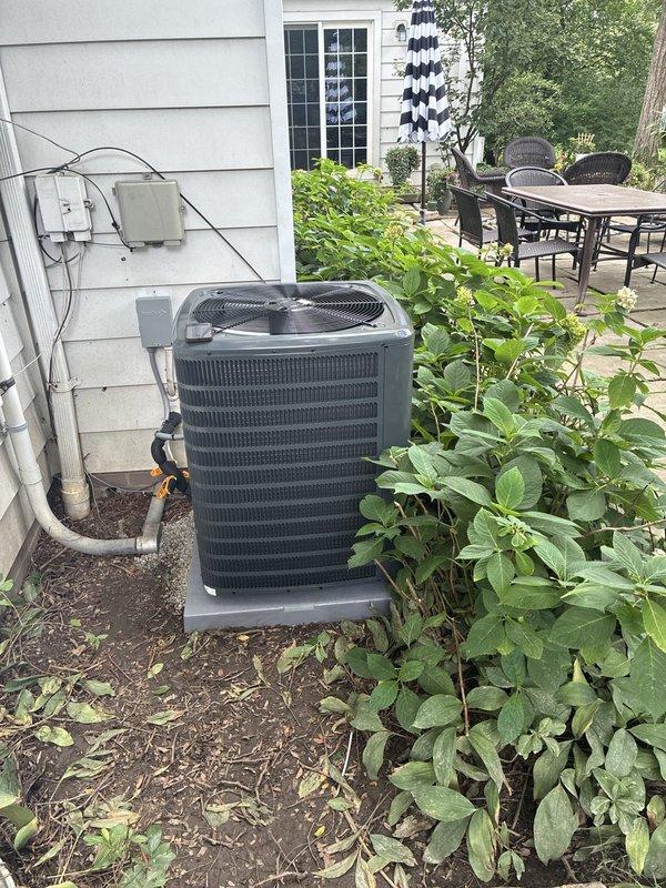 Completed full HVAC system installation including outdoor air conditioning unit positioned on concrete pad with proper electrical connections, junction box, and refrigerant lines secured to exterior wall. Installed York downflow furnace in basement utility area with galvanized metal ductwork and 90-degree elbow configuration, integrated with existing copper piping and gas lines. Whole home surge protection system installed and operational. Final cleanup and system commissioning completed following furnace installation, ensuring all components properly connected and tested for safe operation.