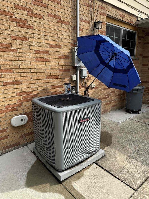 # HVAC Cooling Maintenance Summary

Completed scheduled preventive maintenance on residential air conditioning system. Performed comprehensive inspection of outdoor condensing unit, including verification of proper operation, airflow assessment, and visual examination of all accessible components. Unit found operating within normal parameters with adequate shade protection in place. Documented condition of exterior ventilation grille, noting physical damage to lower louvers with bent and missing slats creating irregular opening. Grille remains functional but compromised structural integrity may affect airflow efficiency and allow debris entry. Photographed damaged section for service records. All electrical connections, meter, and wall-mounted auxiliary equipment visually inspected and found secure. System completing cooling cycle appropriately with no immediate operational concerns identified during maintenance visit.
