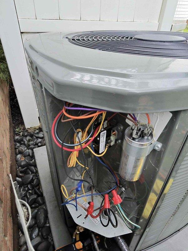 Responded to no cooling complaint on 3-year-old Trane unit following previous chemical cleaning service. Found outdoor condensing unit attempting to start with humming noise but failing to fully engage. Performed electrical diagnostics using clamp meter with unit cover removed, inspecting capacitor, contactor, and associated wiring connections to identify failure point preventing compressor operation.