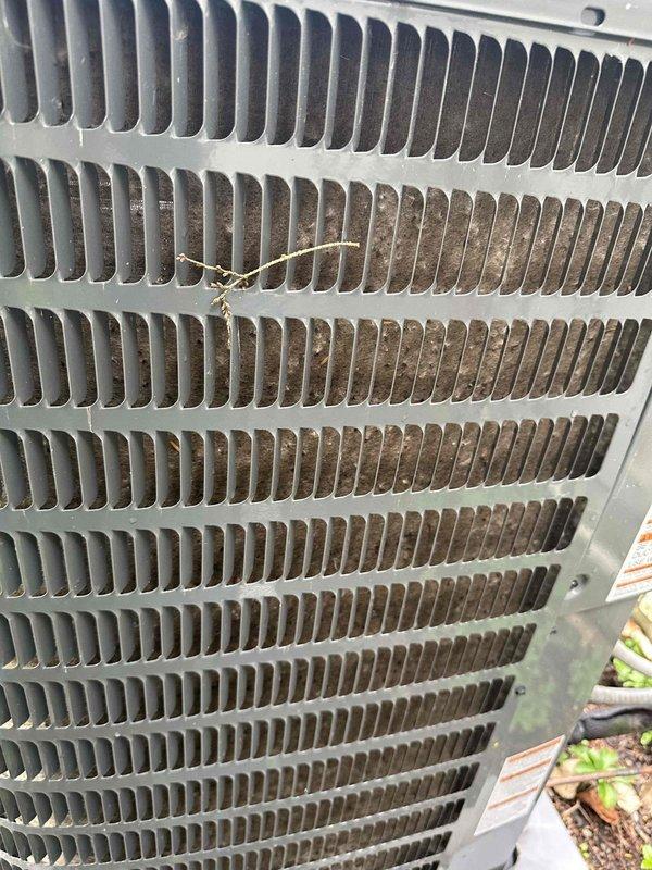 Completed routine HVAC maintenance visit for cooling system. Inspected outdoor condenser unit and found significant accumulation of dirt, dust, and debris throughout heat exchanger coil fins, with plant material lodged in the coil assembly. Performed electrical diagnostics using digital clamp meter to verify system performance and amperage draw. Documented equipment condition through photographic records showing fouled condenser coils requiring attention to maintain optimal heat transfer efficiency and system operation.