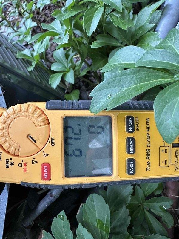 Completed routine HVAC maintenance visit for cooling system. Inspected outdoor condenser unit and found significant accumulation of dirt, dust, and debris throughout heat exchanger coil fins, with plant material lodged in the coil assembly. Performed electrical diagnostics using digital clamp meter to verify system performance and amperage draw. Documented equipment condition through photographic records showing fouled condenser coils requiring attention to maintain optimal heat transfer efficiency and system operation.