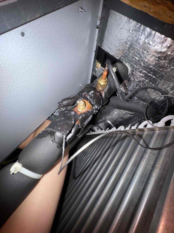 Responded to return service call for system not maintaining temperature setpoint. Inspected refrigerant lines and service valves at indoor unit, noting frost formation on components indicating possible refrigerant flow or metering issues. Documented valve connections and system operation for diagnostic purposes related to ongoing cooling capacity concern.
