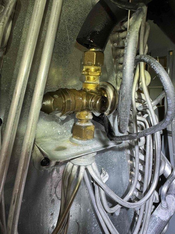 Responded to return service call for system not maintaining temperature setpoint. Inspected refrigerant lines and service valves at indoor unit, noting frost formation on components indicating possible refrigerant flow or metering issues. Documented valve connections and system operation for diagnostic purposes related to ongoing cooling capacity concern.