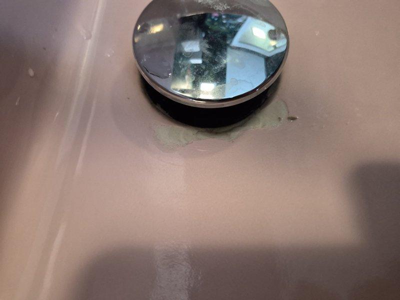 Returned to property to assess reported crack or chip in sink basin. Upon inspection, photographed and documented the sink drain area, noting minor discoloration and residue buildup around the chrome drain cover but no structural damage or cracks present in the porcelain fixture. Confirmed sink integrity is intact and requires no repair at this time.