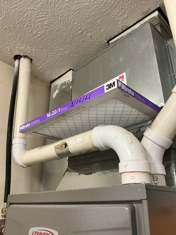 Responded to service call for non-operational air conditioning system with tune-up request. Upon arrival, inspected Lennox HVAC system including furnace unit and air handler assembly. Verified proper installation of 3M Filtrete 16x20x1 air filter in return air section. Examined condensate drain lines and PVC piping for proper drainage and potential blockages. Checked gas line connections at brass shut-off valve and verified secure flexible gas line attachment. Inspected condensate safety switch and overflow protection devices for proper operation. Evaluated ductwork assembly, mounting brackets, and system supports for structural integrity. Performed comprehensive system diagnostics to identify cause of cooling failure and completed preventive maintenance tune-up procedures. Documented equipment condition through photographic records showing filter placement, furnace configuration, and overall system installation.
