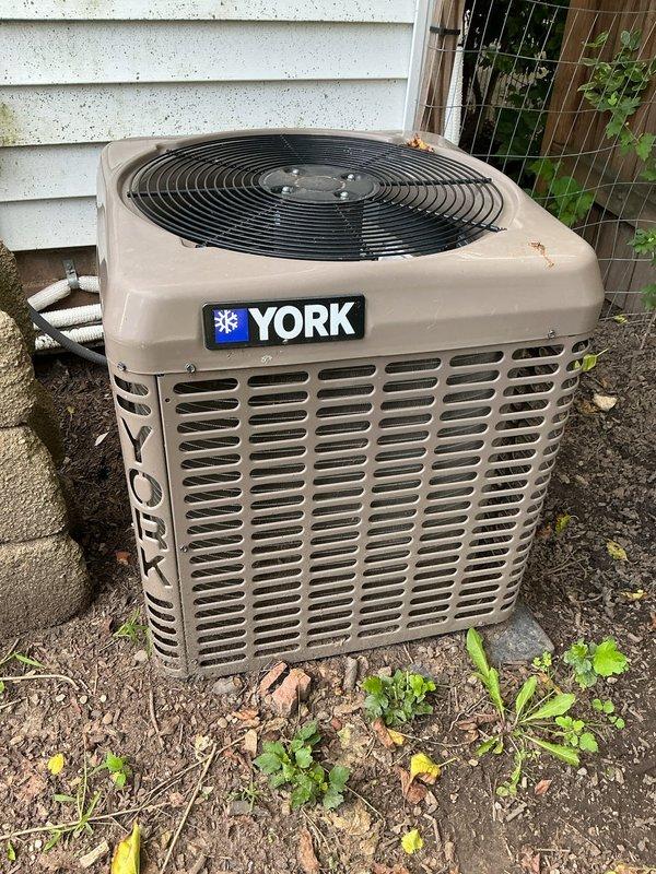 Completed scheduled maintenance on York ductless mini-split cooling system. Inspected wall-mounted indoor air handler unit, accessing internal components by removing front cover panel. Examined air filters which showed moderate dust and dirt accumulation; cleaned filters to restore proper airflow. Inspected evaporator coil assembly and internal components for proper operation. Proceeded to outdoor condenser unit and performed comprehensive inspection of cabinet, fan assembly, and refrigerant line connections. Cleared vegetation and debris from around condenser base to ensure adequate airflow and prevent future obstruction. Verified system operational parameters and confirmed unit cycling properly. All components functioning within normal specifications upon completion of maintenance service.