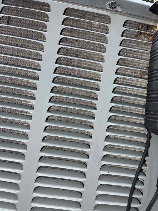Completed routine cooling system maintenance on HVAC unit as part of ongoing preventive maintenance program. Inspected top access panel and ventilation louvers, noting significant accumulation of dirt, dust, and debris throughout louvered vents, with concentrated buildup in rightmost column affecting airflow efficiency. Cleaned ventilation openings and removed particulate matter from mesh screening to restore proper air circulation and prevent system strain. Verified panel latch mechanism and electrical connections secure and functioning properly.