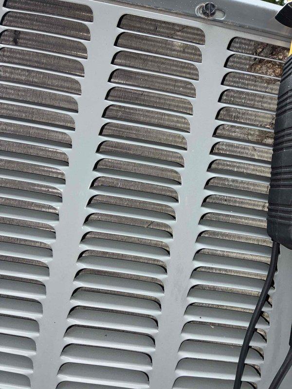 Completed routine cooling system maintenance on HVAC unit as part of ongoing preventive maintenance program. Inspected top access panel and ventilation louvers, noting significant accumulation of dirt, dust, and debris throughout louvered vents, with concentrated buildup in rightmost column affecting airflow efficiency. Cleaned ventilation openings and removed particulate matter from mesh screening to restore proper air circulation and prevent system strain. Verified panel latch mechanism and electrical connections secure and functioning properly.