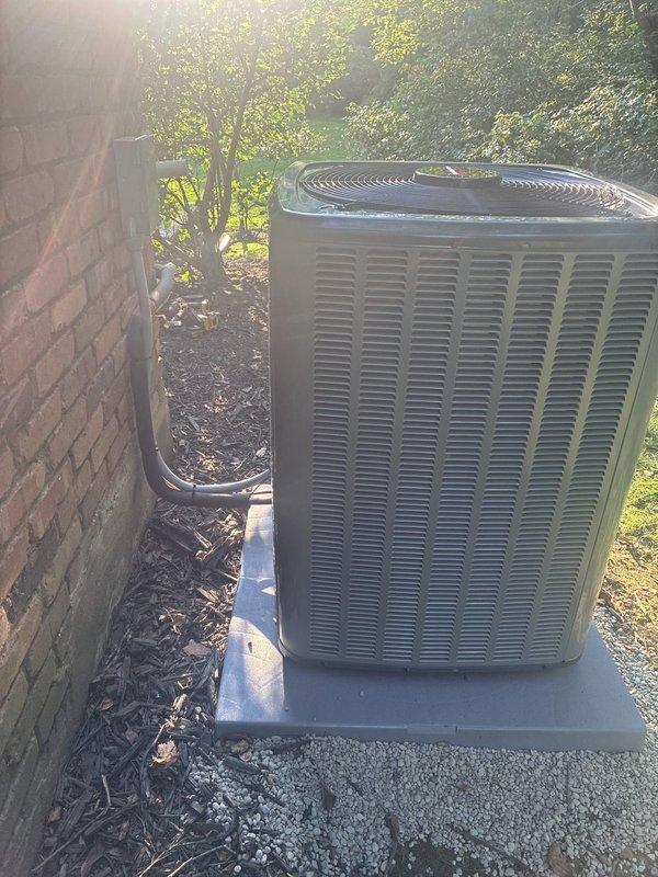 Completed full HVAC system installation including 96% efficiency furnace, air conditioning condenser unit, and whole-home humidifier. New Amana outdoor condenser unit installed on level concrete pad with proper refrigerant line penetration through building exterior, ensuring optimal airflow clearances and stable mounting per manufacturer specifications.