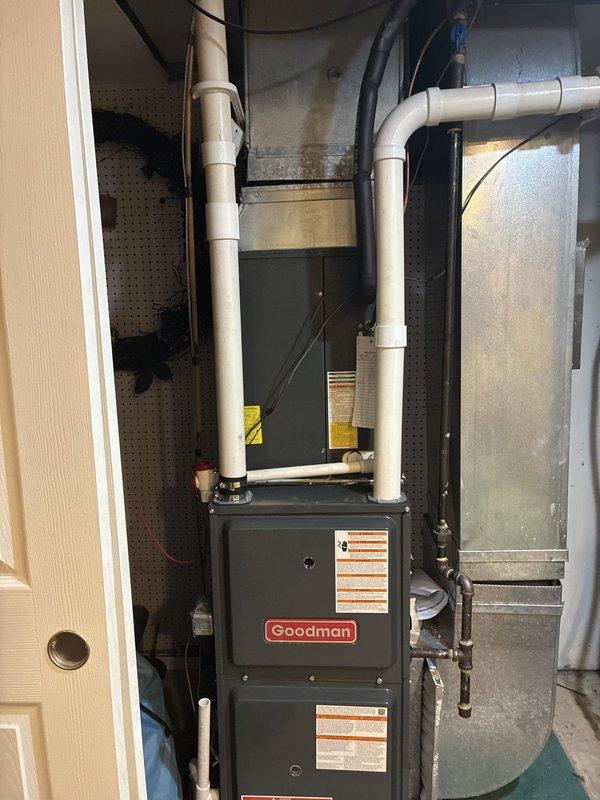 Completed warranty replacement installation of a Goodman 96% AFUE high-efficiency furnace. Installed new unit with proper venting using white PVC piping, connected all electrical components, and verified system operation with digital multimeter showing proper voltage readings at 354.4V EMF. All ductwork connections secured, condensate drainage lines properly routed, and unit tested for safe operation.