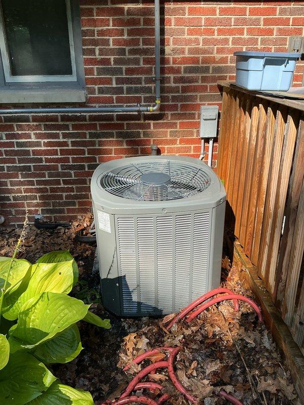 Responded to service call for non-operational air conditioning system affecting entire residence. Upon arrival, inspected five-year-old outdoor condensing unit positioned against exterior brick wall and accessed indoor air handling components in attic space. Performed diagnostic evaluation of system including visual inspection of condenser unit, electrical connections at disconnect box, and indoor air handler with filtration system. Utilized portable lighting to assess attic-mounted equipment and ductwork connections. Documented equipment condition and system configuration through photographic records showing outdoor unit installation with proper clearances and indoor mechanical components including air handler, flexible ductwork, and ventilation grille. Verified system age and configuration matched service records for residential split-system air conditioning unit.