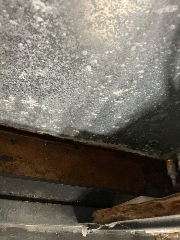 Responded to service call for water dripping from interior pipe connected to air conditioning system. Upon inspection, found condensate drain line issue causing water overflow, with extensive corrosion and moisture damage visible on evaporator coil housing and drain pan assembly. Cleared blocked condensate line, verified proper drainage, and confirmed system operation with no further water leakage detected.