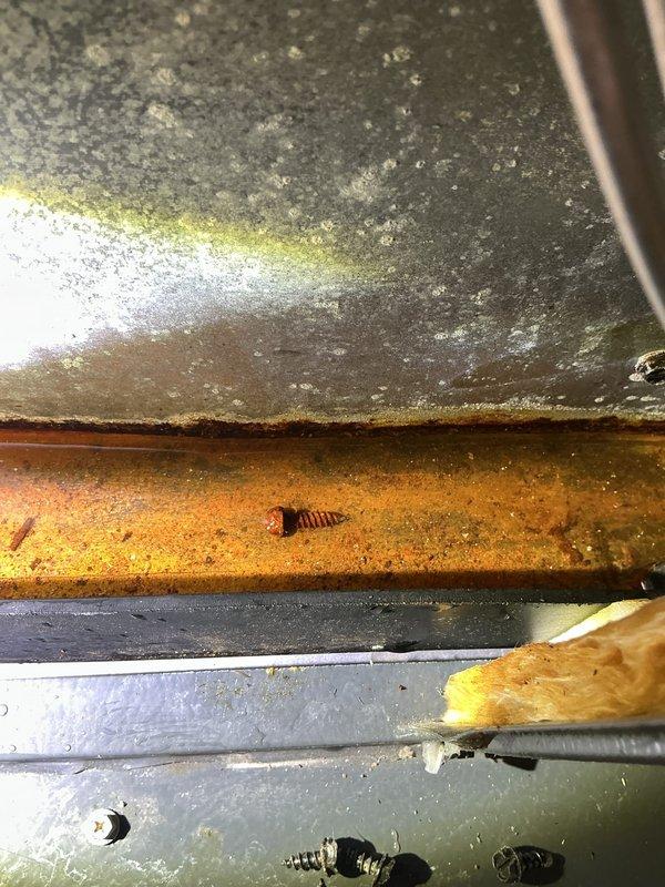 Responded to service call for water dripping from interior pipe connected to air conditioning system. Upon inspection, found condensate drain line issue causing water overflow, with extensive corrosion and moisture damage visible on evaporator coil housing and drain pan assembly. Cleared blocked condensate line, verified proper drainage, and confirmed system operation with no further water leakage detected.