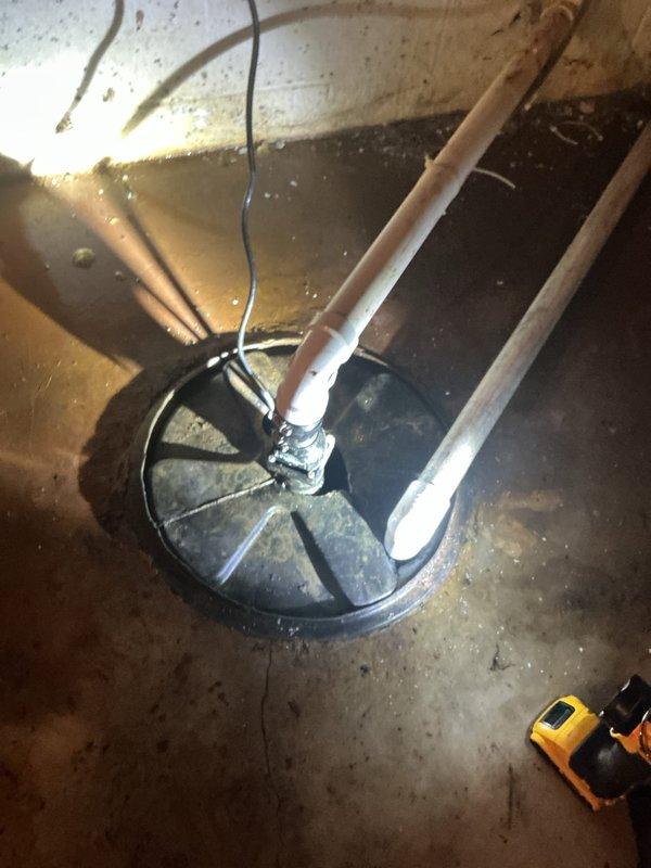 Conducted comprehensive sump pump replacement estimate for failed unit in basement installation. Assessed existing system including corroded copper discharge piping with significant oxidation at elbow joint, PVC vertical discharge pipe, and basin configuration with standing water present. Documented complete failure of current pump and evaluated discharge line condition showing advanced deterioration requiring replacement alongside pump unit.