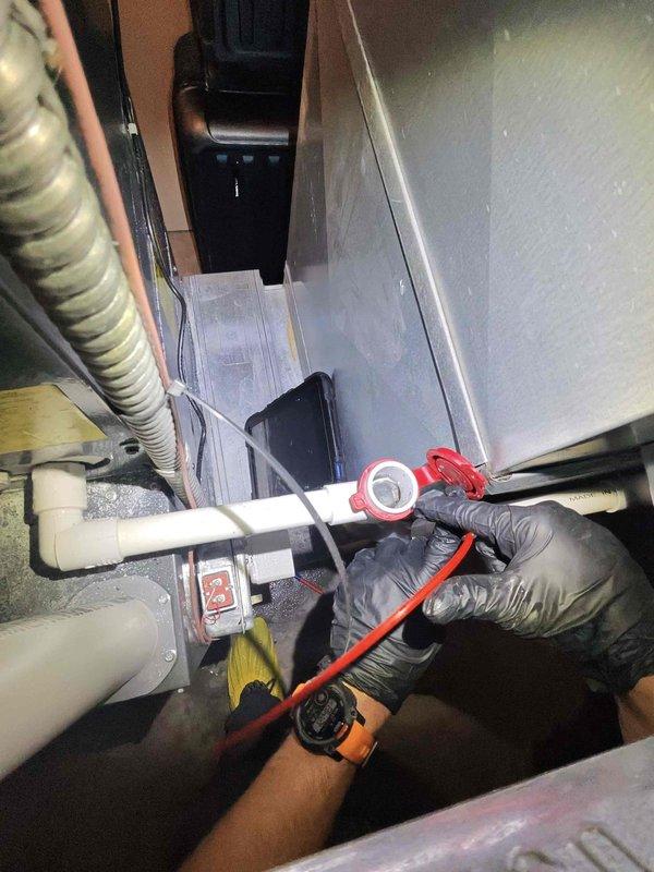 Responded to customer report of furnace leaking extensively. Upon inspection, identified issue originating from evaporator coil assembly and associated condensate drainage system in attic installation. Examined A-coil configuration with serpentine copper refrigerant lines and finned heat exchanger, noting proper coil orientation but potential drainage concerns. Inspected condensate drain lines including PVC piping and connections in confined utility space beneath unit. Assessed drain pan condition, P-trap functionality, and primary/secondary drain line routing. Documented system configuration and leak source with photographic evidence for service records and recommended corrective action to resolve water intrusion issue.