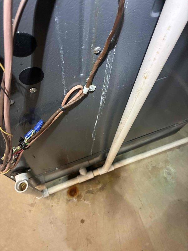 # HVAC Service Call - Water Leakage Investigation

Responded to callback regarding persistent water leakage on top of air conditioning unit following previous day's service visit. Upon arrival, conducted thorough inspection of the system and surrounding area to identify source of continued moisture issue.

Accessed crawl space beneath unit and documented extensive standing water accumulation on waterproof liner throughout the confined area. Multiple puddles with murky, discolored water observed across gray membrane surface, indicating ongoing drainage problem. Inspected overhead PVC drainage pipes and connections for potential leak points or blockages that could be contributing to water presence.

Examined HVAC equipment installation area and photographed refrigerant line set, condensate drain components, and associated piping. Black condensate drain line inspected for proper pitch and flow. Copper refrigerant lines and blue/silver fittings checked for condensation issues. White PVC co