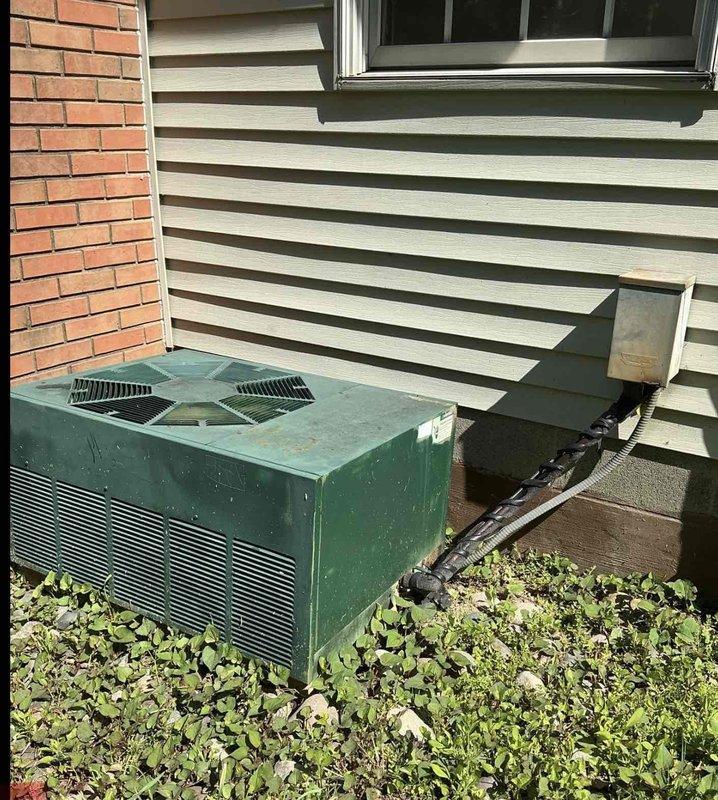 Conducted on-site evaluation of existing outdoor HVAC system to provide replacement options for the homeowner. The current unit, a teal-colored air conditioning system positioned on a concrete pad against the home's exterior, showed signs of age and weathering with visible discoloration and dirt accumulation on the metal surfaces. Assessed the equipment's condition, noting the existing installation configuration including ductwork connection to the home and unit placement relative to the foundation. Documented the system with photographs for estimate preparation purposes. Discussed full replacement options with the homeowner, taking into account the unit's deteriorated condition and potential issues from previous repair attempts. Provided technical recommendations for complete system replacement to ensure optimal performance and reliability.