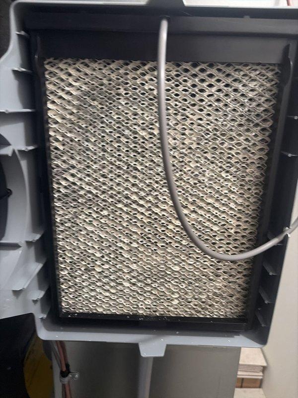 # HVAC Cooling Maintenance Service

Completed comprehensive cooling system maintenance as part of scheduled preventive service program. Performed thorough inspection of air conditioning equipment and associated components to ensure optimal system performance and reliability.

Inspected humidifier unit integrated with HVAC system, documenting condition of evaporator pad media. Observed honeycomb-patterned filter element showing mineral deposits and discoloration consistent with normal operational use. Verified water distribution line positioned through center of pad assembly. Examined housing integrity and airflow direction components for proper function.

Conducted electrical diagnostics using digital multimeter to verify system voltage, amperage, and electrical connections. Tested control circuits and safety switches to ensure proper operation within manufacturer specifications. All electrical readings recorded and found within acceptable parameters.

Inspected accessible ductwork, pl