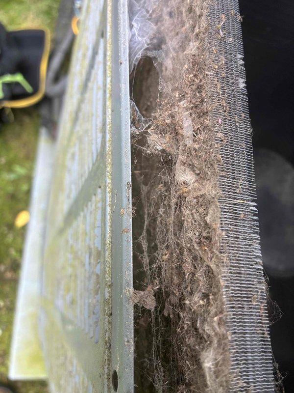 Completed routine HVAC cooling maintenance on aging system with furnace confirmed operational. Inspection revealed significant condenser coil contamination with heavy dust, dirt, and debris accumulation restricting airflow, along with cobweb buildup across fins indicating extended period without service. Blower motor assembly showed normal wear consistent with age, with surface corrosion noted on shaft but unit functioning properly.