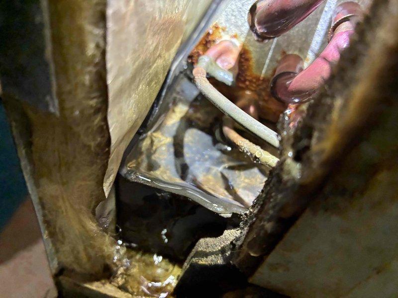 Responded to service call for air conditioning system leaking water in basement. Upon inspection, found condensate drain line with signs of blockage and extensive corrosion on evaporator coil housing and refrigerant lines, indicating prolonged moisture exposure. Cleared condensate drain obstruction, verified proper drainage flow, and advised customer of deteriorated equipment condition requiring future attention to prevent recurring issues.