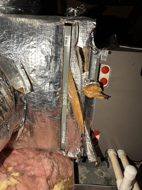 Responded to service call for filter replacement on 11-year-old air conditioning system. Previous technician was unable to locate filter access point. Upon inspection of attic-mounted air handler unit, identified that system utilizes a return air filter grille located elsewhere in the home rather than at the equipment. Verified air handler installation and ductwork configuration, noting reflective insulated supply plenum with some degradation to exterior vapor barrier wrap. Confirmed proper refrigerant line connections and condensate drain routing via white PVC piping. Educated customer on filter location and proper maintenance procedures for their specific system configuration to ensure adequate airflow and system efficiency.