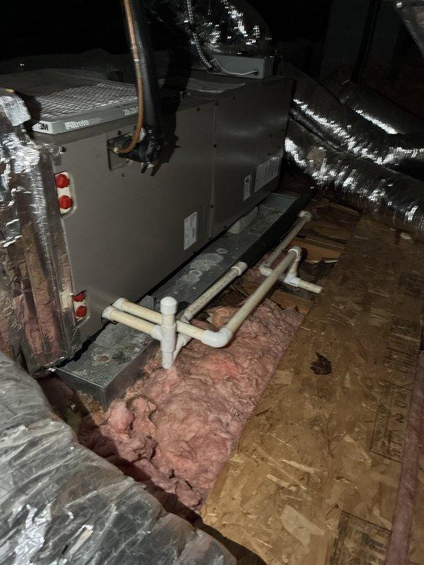 Responded to service call for filter replacement on 11-year-old air conditioning system. Previous technician was unable to locate filter access point. Upon inspection of attic-mounted air handler unit, identified that system utilizes a return air filter grille located elsewhere in the home rather than at the equipment. Verified air handler installation and ductwork configuration, noting reflective insulated supply plenum with some degradation to exterior vapor barrier wrap. Confirmed proper refrigerant line connections and condensate drain routing via white PVC piping. Educated customer on filter location and proper maintenance procedures for their specific system configuration to ensure adequate airflow and system efficiency.