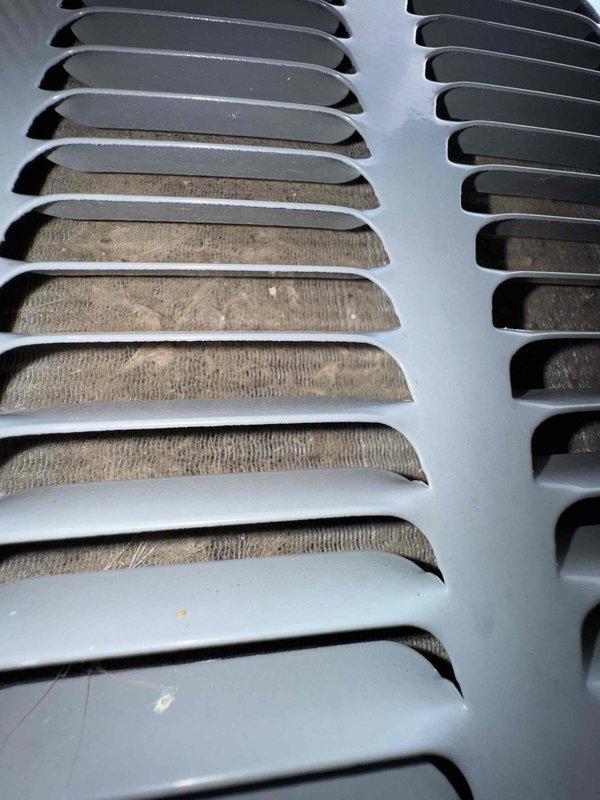 Responded to water leak complaint on 11-year-old Amana AC unit with water present on laundry room floor. Upon inspection, discovered evaporator coil heavily contaminated with dust and debris accumulation, particularly on left section of cooling fins, causing restricted airflow and drain pan overflow. Cleaned evaporator coil fins, cleared primary condensate drain line, verified proper drainage, and tested system operation to confirm resolution of leak issue.