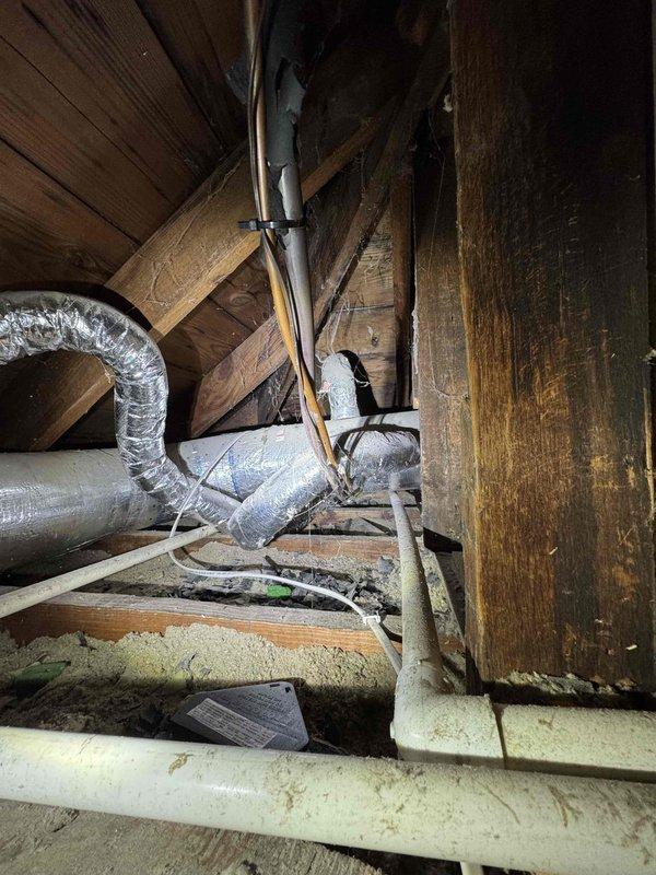 Responded to service call for rodent damage to air conditioning system wiring in attic space. Upon inspection, confirmed that rodents had chewed through insulation covering on electrical wiring to AC unit, leaving conductors exposed. Documented damage with photographs showing affected wiring runs and overall attic conditions including HVAC ductwork routing and structural layout. Advised customer of findings and necessary repairs to restore safe electrical connections and proper insulation coverage to prevent further deterioration or potential electrical hazards.