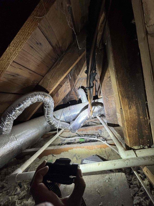 Responded to service call for rodent damage to air conditioning system wiring in attic space. Upon inspection, confirmed that rodents had chewed through insulation covering on electrical wiring to AC unit, leaving conductors exposed. Documented damage with photographs showing affected wiring runs and overall attic conditions including HVAC ductwork routing and structural layout. Advised customer of findings and necessary repairs to restore safe electrical connections and proper insulation coverage to prevent further deterioration or potential electrical hazards.