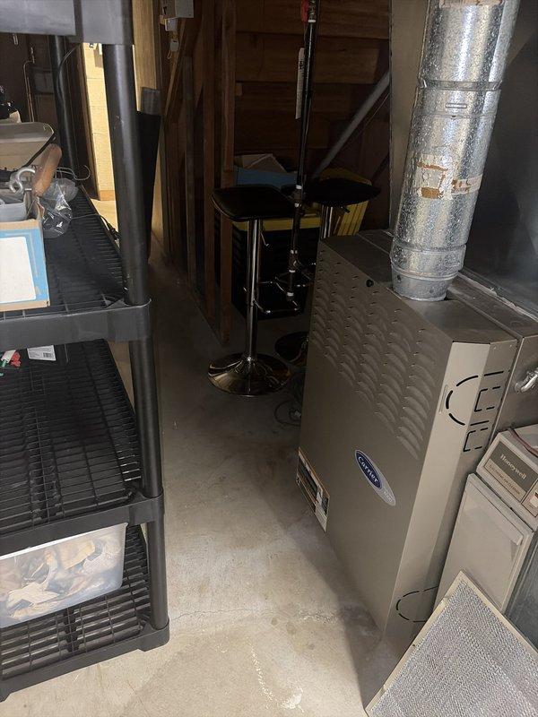 Performed comprehensive heating and cooling system evaluation for new homeowner following promotional system check offer. Conducted complete walk-through inspection of Carrier furnace and air conditioning system in basement utility area, documenting equipment condition and operational status with temperature readings and equipment photography. System ages undetermined at time of inspection; no immediate issues or concerns reported by homeowner, equipment found in serviceable condition with proper ductwork connections intact.