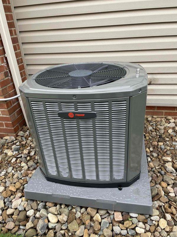 Completed full HVAC system installation including furnace, air conditioning unit, and ductwork liner. Installed Trane brand outdoor condensing unit on concrete pad with proper clearance from structure, positioned on river rock bed for drainage. Unit features protective mesh grilles and fan assembly, mounted against exterior wall with appropriate electrical connections and refrigerant lines. System tested and verified operational upon completion.