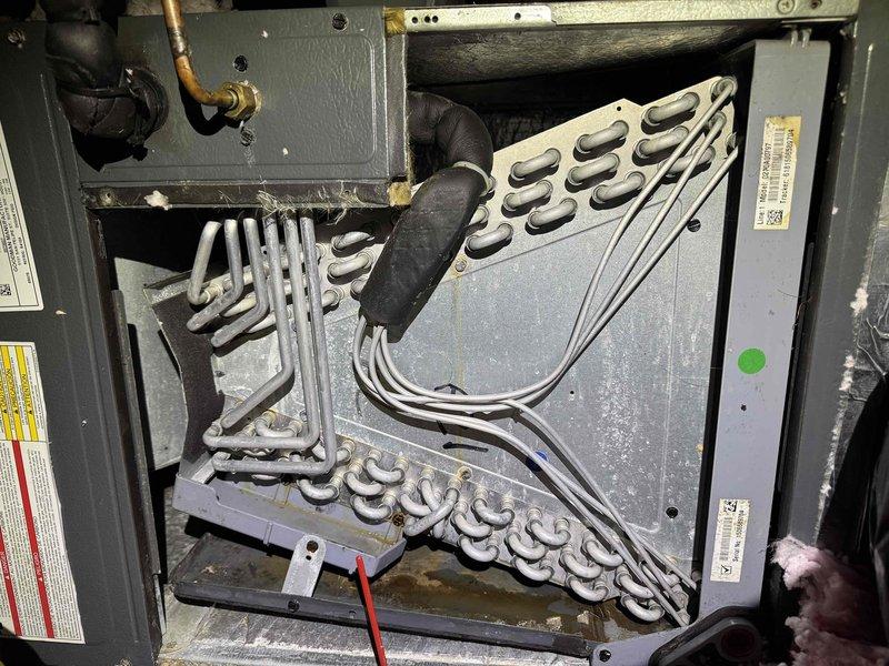 # HVAC Evaporator Coil Cleaning and Drain Maintenance

Responded to service call for HVAC system maintenance. Upon inspection, found evaporator coil with significant dust accumulation and heavy ice/frost buildup covering the serpentine refrigerant tubing, indicating restricted airflow and potential drainage issues. 

Performed comprehensive evaporator coil cleaning to remove dust, debris, and frost accumulation from all accessible surfaces of the heat exchanger assembly. Cleared ice buildup from coil surfaces to restore proper heat transfer efficiency. Cleaned condensate drain system and installed drain tabs to prevent algae growth and maintain clear drainage pathway. 

Verified proper airflow through coil assembly and confirmed condensate drainage functioning correctly. System restored to normal operating condition with improved heat exchange efficiency and preventative maintenance measures in place.