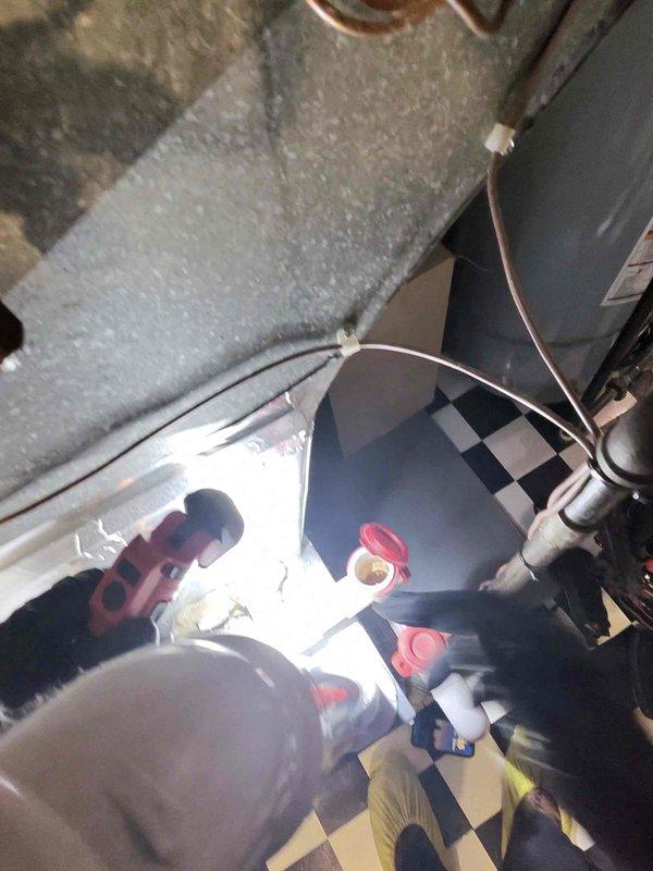 Responded to recurring water leak complaint on 11-year-old Amana AC unit located in garage. Inspected evaporator coil, drain pan, and condensate drainage system following two previous service visits. Found condensate drain line obstruction and improper pitch causing water to back up into basement/laundry room area. Cleared blockage, adjusted drain line slope, and verified proper drainage flow. Tested system operation through complete cooling cycle to confirm leak resolution.