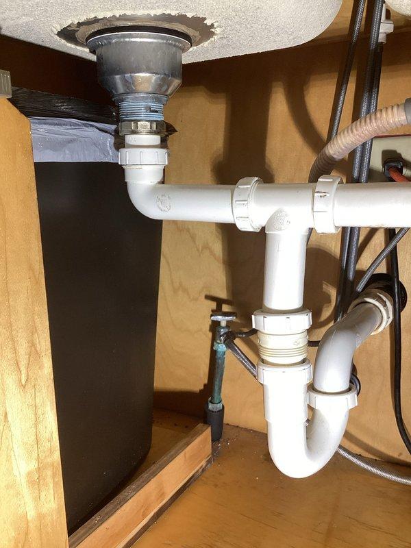 Responded to service call for disconnected kitchen sink drain assembly. Upon inspection, found the P-trap connection beneath the kitchen sink had separated, causing the drain line to become detached from the sink basin. Reconnected and properly secured all PVC pipe fittings and coupling nuts in the P-trap assembly. Verified all connections were tight and leak-free, then tested the drain system to ensure proper water flow and drainage function.