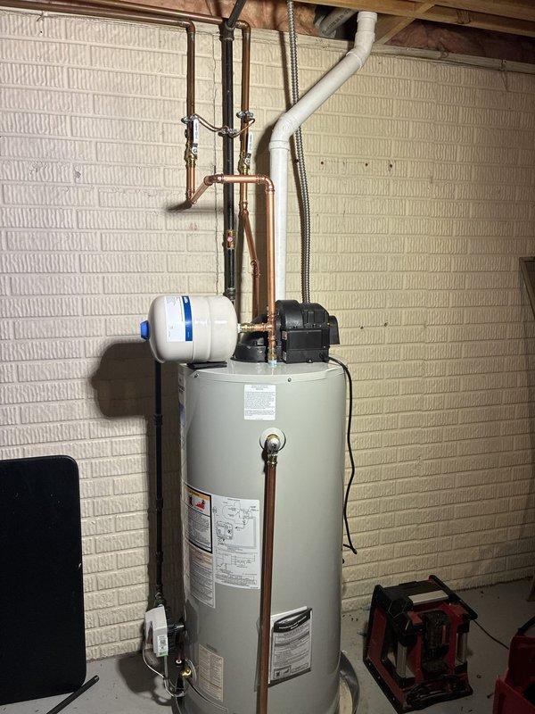 Completed installation of 50-gallon power vent water heater in residential basement utility area. Unit was properly connected with copper supply lines, PVC venting, expansion tank, and circulation pump, with all plumbing connections secured and tested for proper operation. Installation included mounting expansion tank to wall, routing exhaust venting through existing penetration, and verifying all safety labels and manufacturer specifications were visible per code requirements.