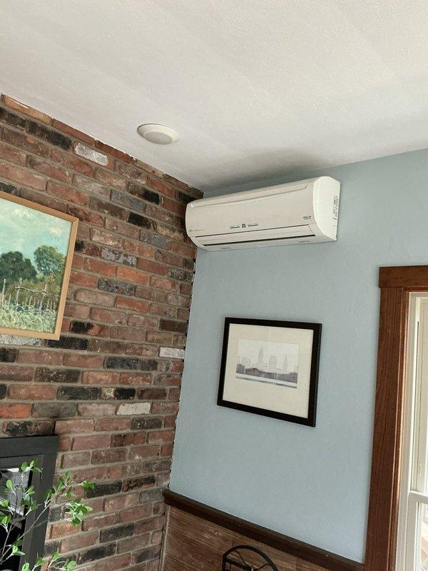 Conducted estimate for replacement of 25-year-old non-functional ductless mini-split system including both outdoor condenser unit and indoor air handler. Existing system has failed beyond repair and requires complete replacement. Documented current equipment installation locations, with outdoor unit positioned beneath elevated deck structure and indoor wall-mounted unit installed in living space with exposed brick wall. Assessed electrical connections, refrigerant line routing, and mounting configurations to determine replacement specifications and installation requirements.