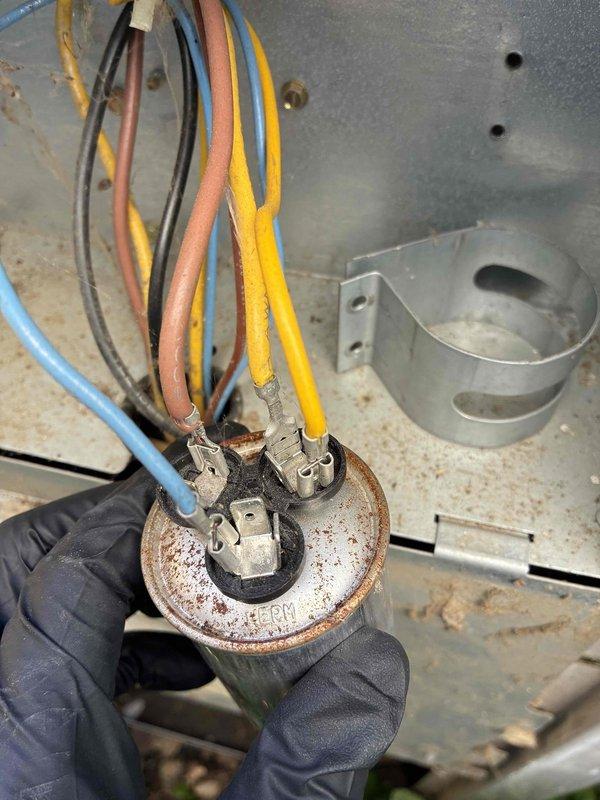 Responded to no cooling complaint on first floor air conditioning system. Upon inspection, found heavily corroded dual run capacitor with significant rust and oxidation on terminals and housing. Contactor assembly also showed signs of age with oxidized terminals and wear consistent with 10+ year old equipment. Removed failed capacitor, cleaned terminal connections, and installed replacement capacitor with proper wire connections to compressor and condenser fan motor circuits. Verified all electrical connections at contactor were secure and tested system operation to confirm cooling restored.