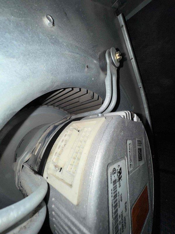 Responded to service call for 15-year-old furnace system requiring blower motor evaluation and repair. Upon inspection, assessed the existing blower motor assembly and mounting configuration within the air handler cabinet. Performed diagnostic evaluation to compare repair options and provided technical assessment of the motor condition, mounting hardware, and electrical connections. Documented equipment condition with detailed photography showing the cylindrical blower motor with manufacturer specifications, mounting bracket assembly, electrical conduit connections, and blower housing components with discharge venting system.