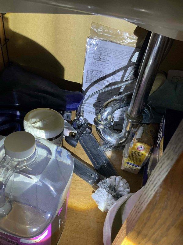 Completed plumbing inspection to assess feasibility of water softener installation. Evaluated existing under-sink plumbing configuration and water heater location to determine optimal placement and connection points for softener system. Documented current plumbing infrastructure including P-trap assembly, supply lines, and available cabinet space beneath sink. Photographed water heater unit and surrounding utility area to assess installation requirements and clearance specifications for water softener equipment.